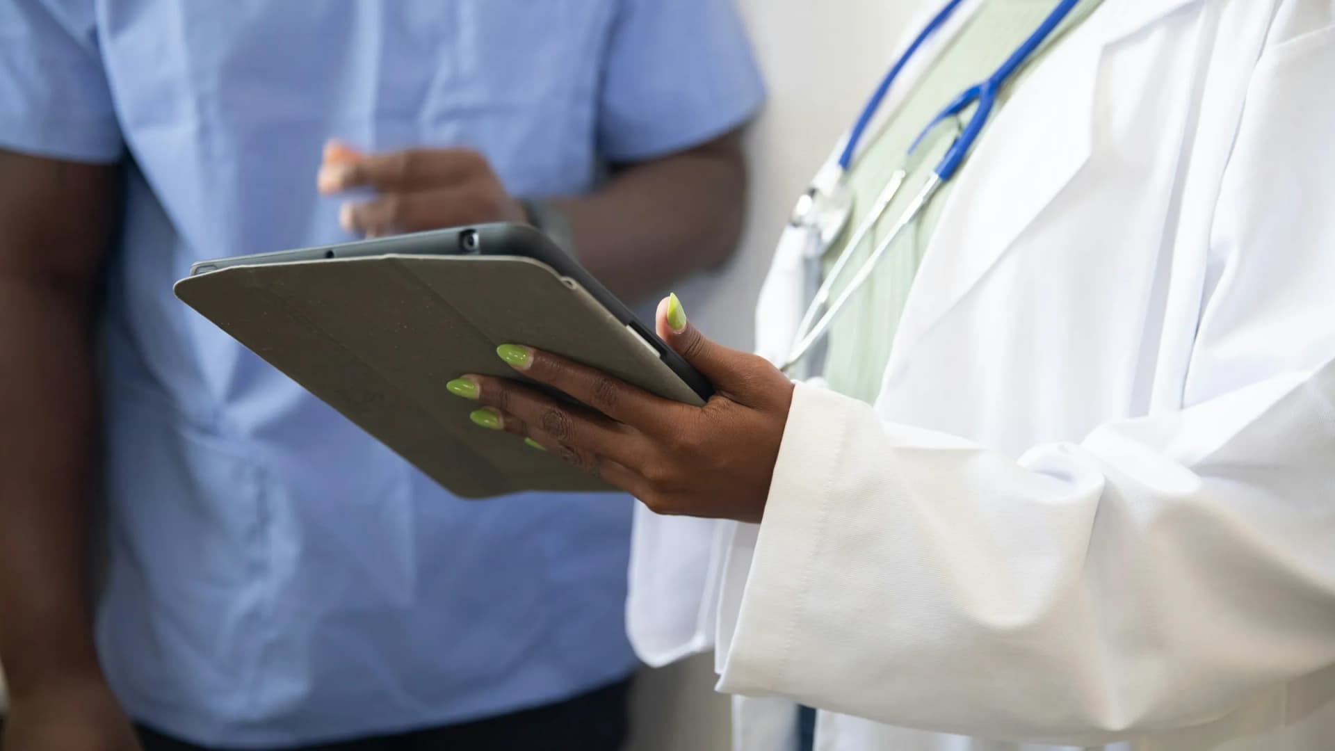 A nurse and a doctor reviewing notes together on a tablet