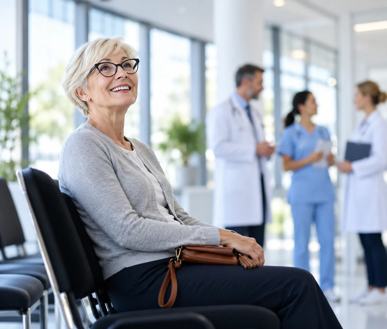 A smiling patient waiting at the clinic while the care team talks in the background